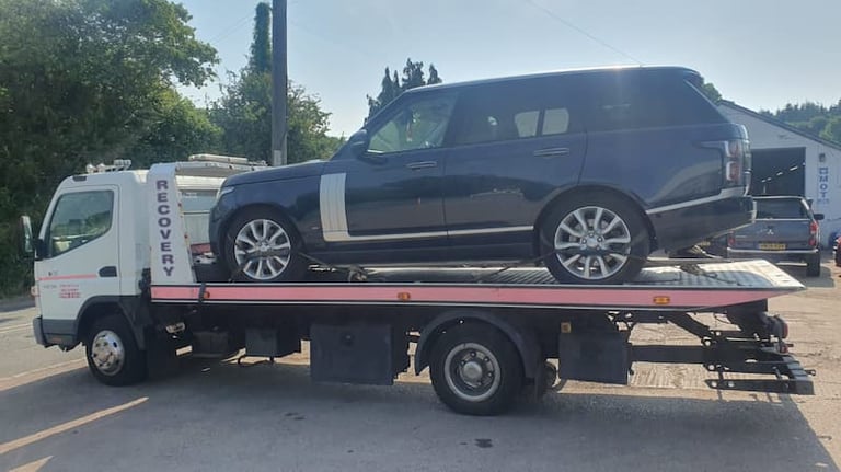 a car being towed down a street in a parking lot