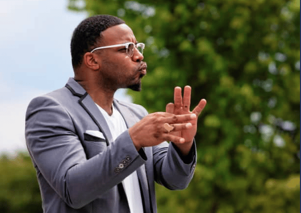 a man in a suit and sunglasses is holding a cell phone