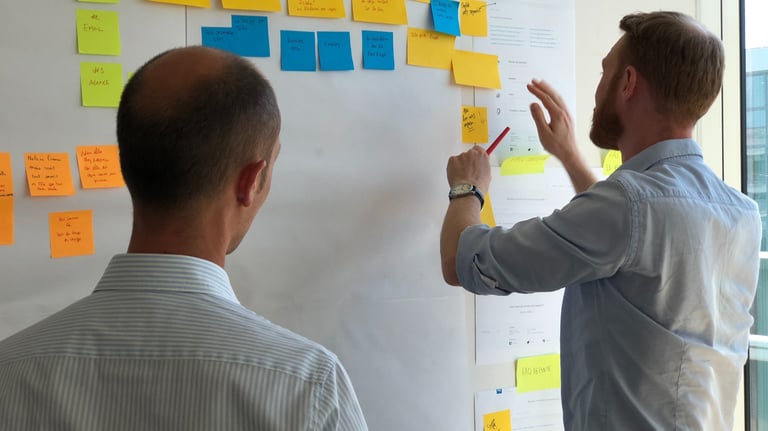 due uomini di spalle che aggiungono post a una vision board