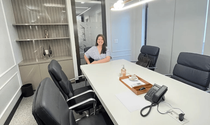 a woman sitting at a table with a phone in front of her