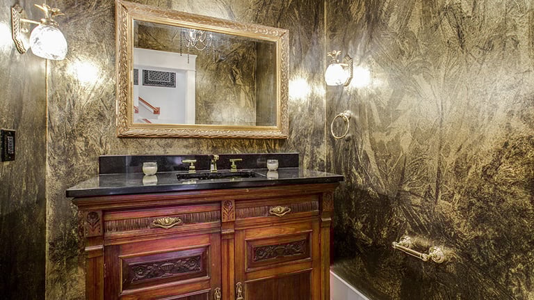 Luxury powder room with wooden vanity, and ornate mirror.