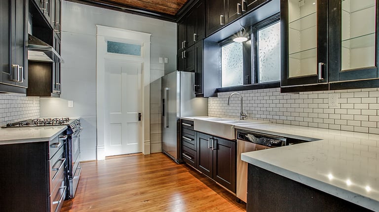 Modern kitchen with dark cabinets, white subway tile backsplash, and rustic wood ceiling.