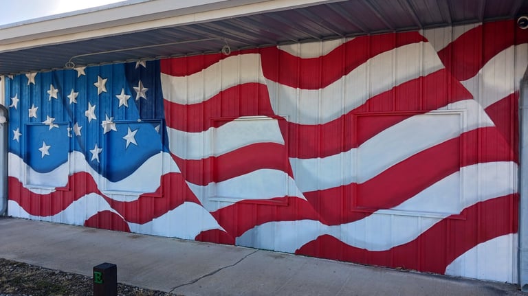 A metal building exterior featuring a patriotic American flag mural with red and white stripes and white stars.
