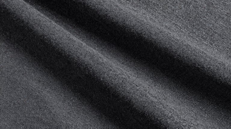 Clean, studio photography showing the texture of a charcoal grey linen fabric. The lighting is soft, emphasizing the natural weave of the textile.