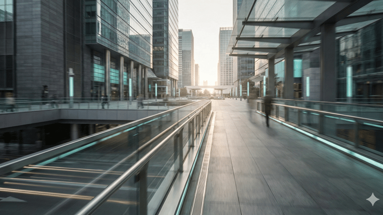 Modern glass office buildings and a pedestrian skywalk in a city business district at sunset.
