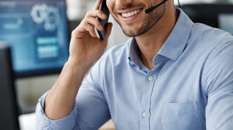 Smiling male customer support agent wearing a headset while working in a modern office.