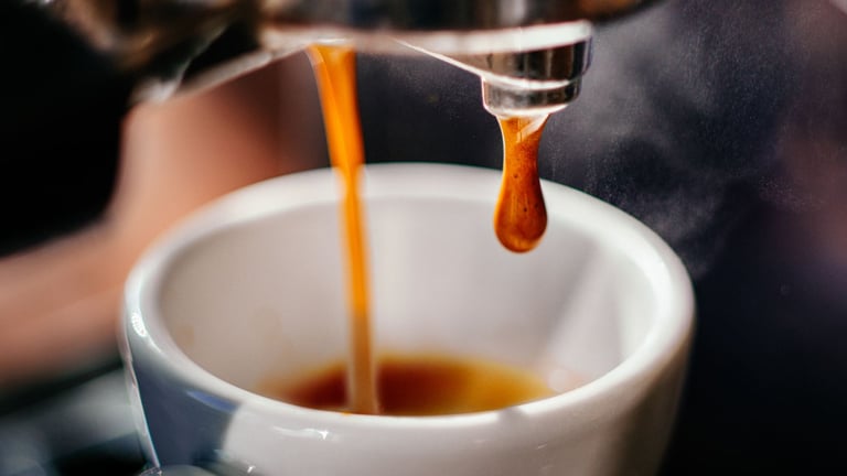 a person is pouring a cup of coffee into a cup