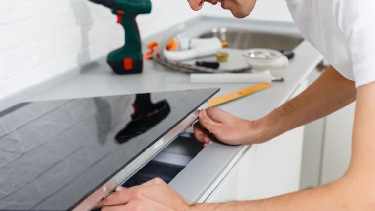 a man is fixing a stove top in a kitchen