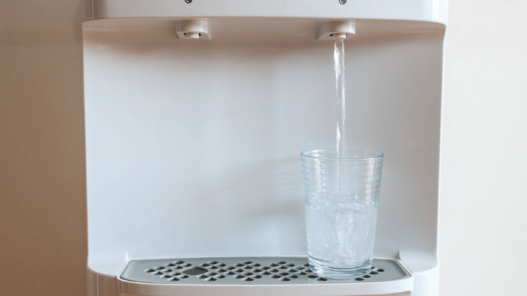 a glass of water is being poured into a water dispenser