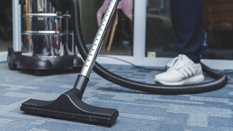 a person is cleaning a carpet with a vacuum
