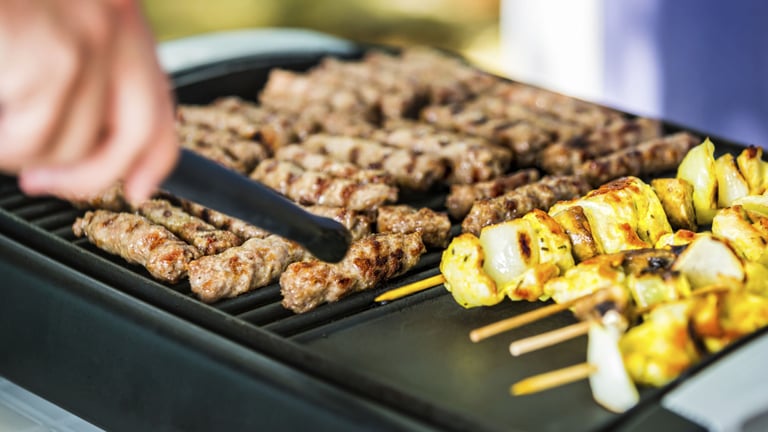 a person is cooking on a grill with skewers