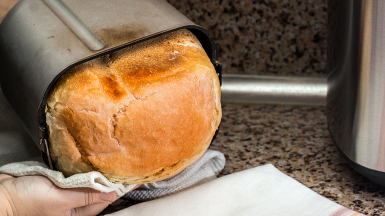 a person holding a loafed bread in a kitchen
