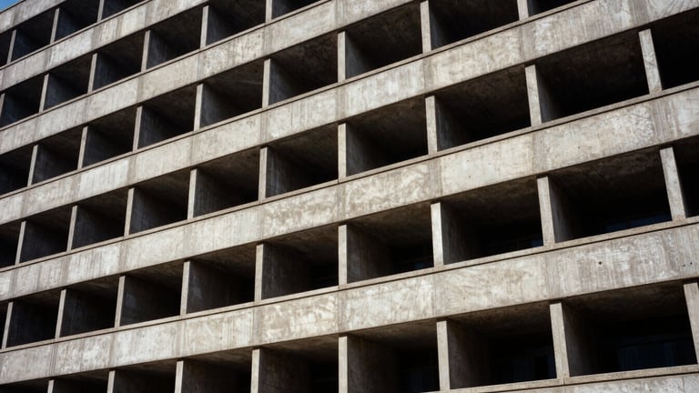 Wide panoramic view of a brutalist building facade, harsh direct sunlight creating deep shadows, strict orthogonal lines, architectural film photography, 35mm lens.