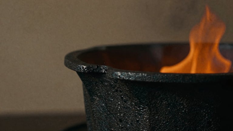 Close-up macro of hot-forged black iron with raw scale texture, glowing orange embers in the background, deep shadows, moody editorial photography, 35mm film