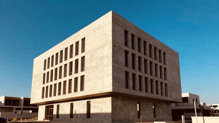 Wide architectural shot of a modern minimalist concrete office building in Casablanca, sharp geometric lines, bright Moroccan afternoon sunlight, deep blue sky, 35mm architectural photography