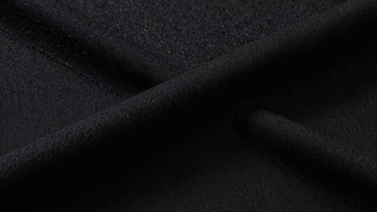 Extreme close-up of heavy-weight black cotton fabric weave, sharp directional studio lighting revealing the coarse, premium texture and thick structural seams.