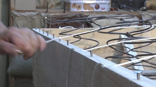 Un artisan matelassier guindant un sommier