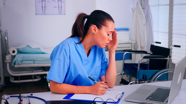 overworked nurse wrinting on clipboard working