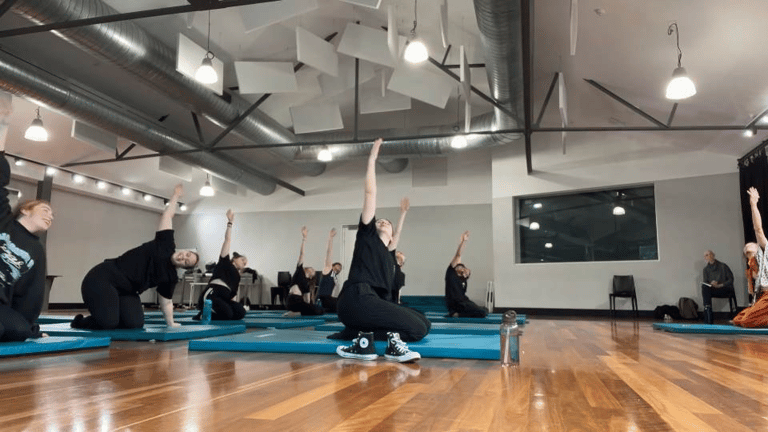 a group of people doing yoga exercises on a wooden floor