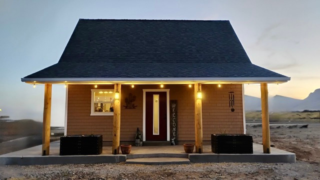 Small cottage at sunset with porch lights on