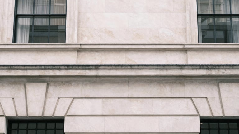 Architectural detail of a Portland stone facade in London, soft overcast daylight, clean editorial crop.