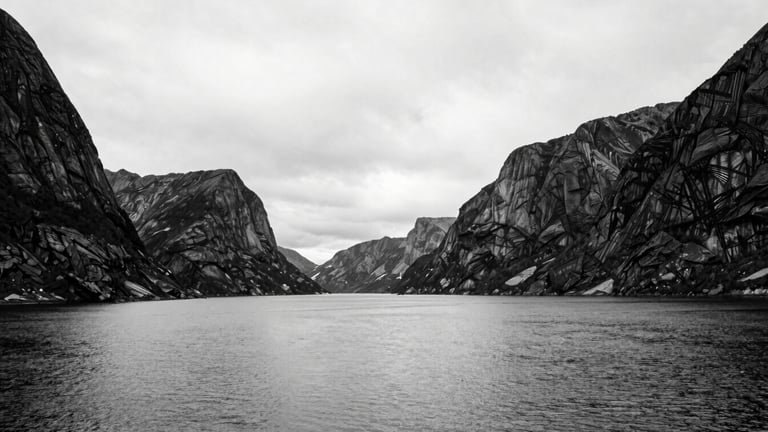 Extremely wide black and white shot of a vast Norwegian fjord landscape, empty, silent, with dramatic high contrast between water, sky, and towering rock formations, minimalist, 35mm