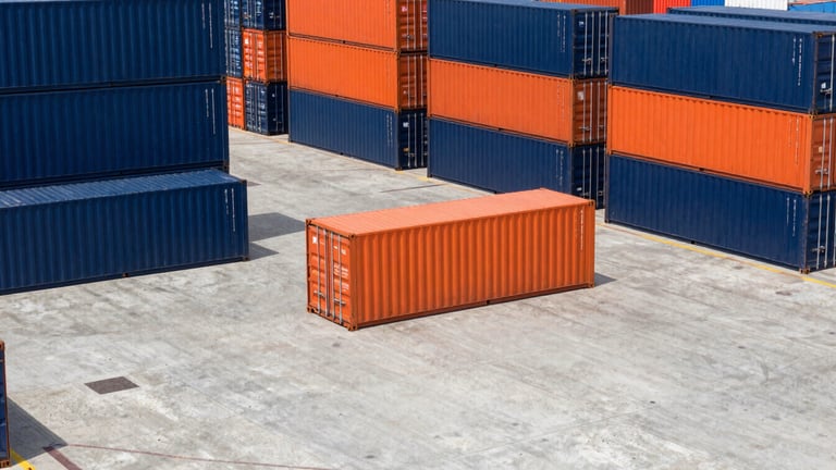Wide-angle photograph of active cross-docking operations, cargo containers being unloaded at a clean concrete dock, bright daylight, high contrast navy and orange tones.