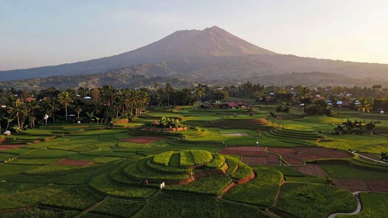 Panoramic environmental drone shot of lush green agricultural land and terraced rice fields in Cigombong, Mount Salak majestic in the background under soft golden hour sun, 35mm lens