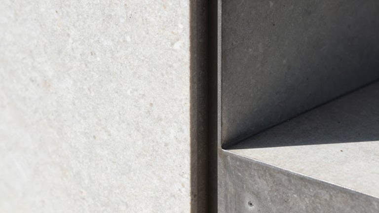 Macro detail shot of a sharp shadow-gap join between raw steel and hand-aligned travertine, crisp natural daylight, high-contrast, editorial architectural photography.