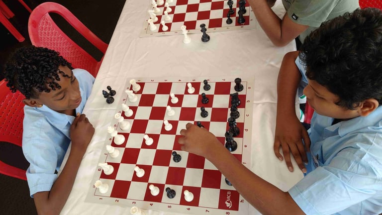 Two students in school uniforms playing a competitive game of chess on a red and white board.