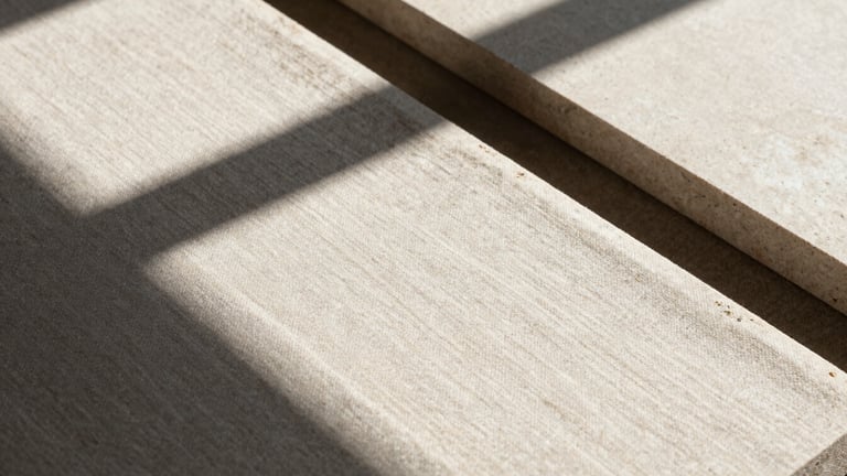 Close-up of tactile design materials, raw linen and limestone under harsh direct sunlight with sharp dramatic shadows, neutral tones, 35mm lens