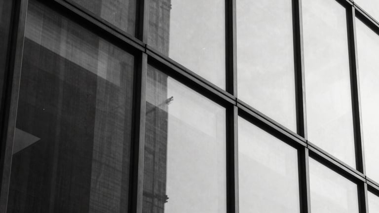 Abstract close-up of a glass facade reflecting sharp architectural lines, hard direct sunlight, high contrast, 35mm.