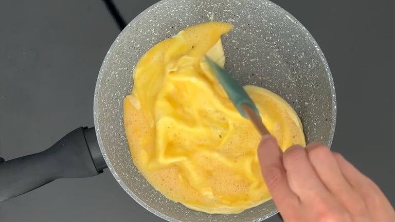 Cuoci l'omelette, usa una spatola per spingere delicatamente i bordi verso il centro creando la form