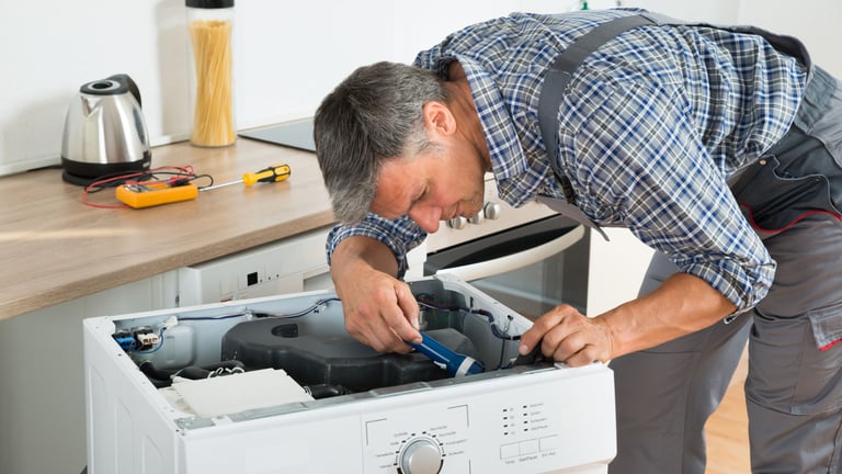 a man in a plaid shirt is fixing a dishwasher