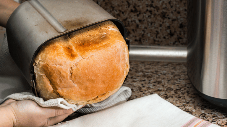 a person holding a loafed bread in a kitchen