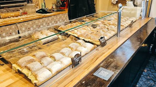 Freshly baked puff pastry rolls with sweet and savory fillings displayed in a bakery glass case.
