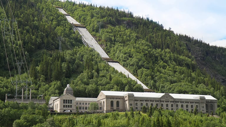 A large industrial building sits at the base of a green slope-NIA used with permission