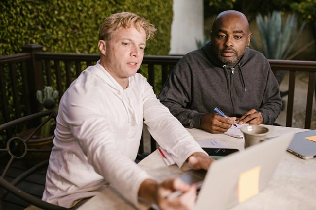 deux hommes travaillant sur un ordinateur pour organiser la logistique du team building