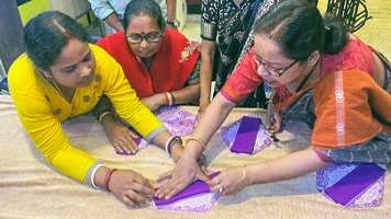 Three women discussing how to make fabric sanitary napkins