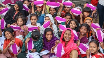 About 20 girls smiling and holding up a Hanaru reusable sanitary napkin