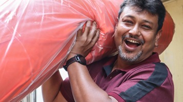 A man smiling and carrying a roll of fleece fabric on his shoulder