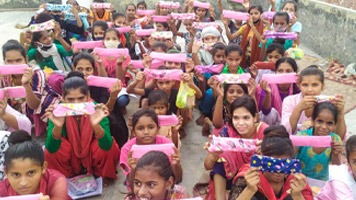 Thirty girls on a flat rooftop holding up Hanaru's sanitary napkins