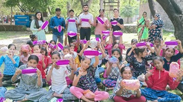 Girls and eight adults in a park holding up Hanaru's sanitary napkins.