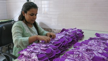 Priyanka seated tying up packs of reusable sanitar napkins. 