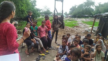 Pooja giving a talk to a group of girls on the edge of a slum.
