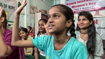 Girl in classroom with hand up.