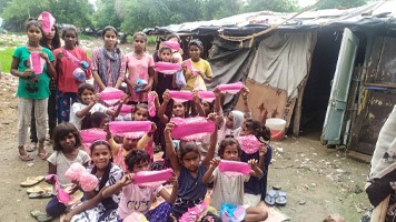 About twenty girls in a slum holding up Hanaru's sanitary napkins.