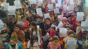 Group of girls sitting on the floor holding paper sheets menstrual education.