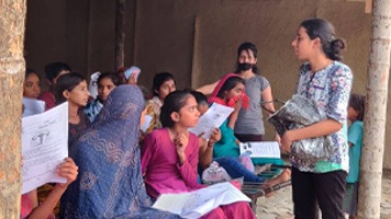 Group of girls listening to Pooja G giving menstrual education.