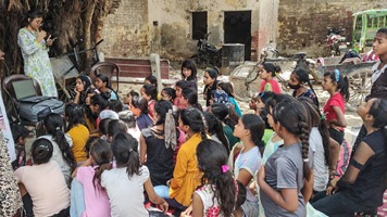 Group of girls listening to Pooja G giving menstrual education.